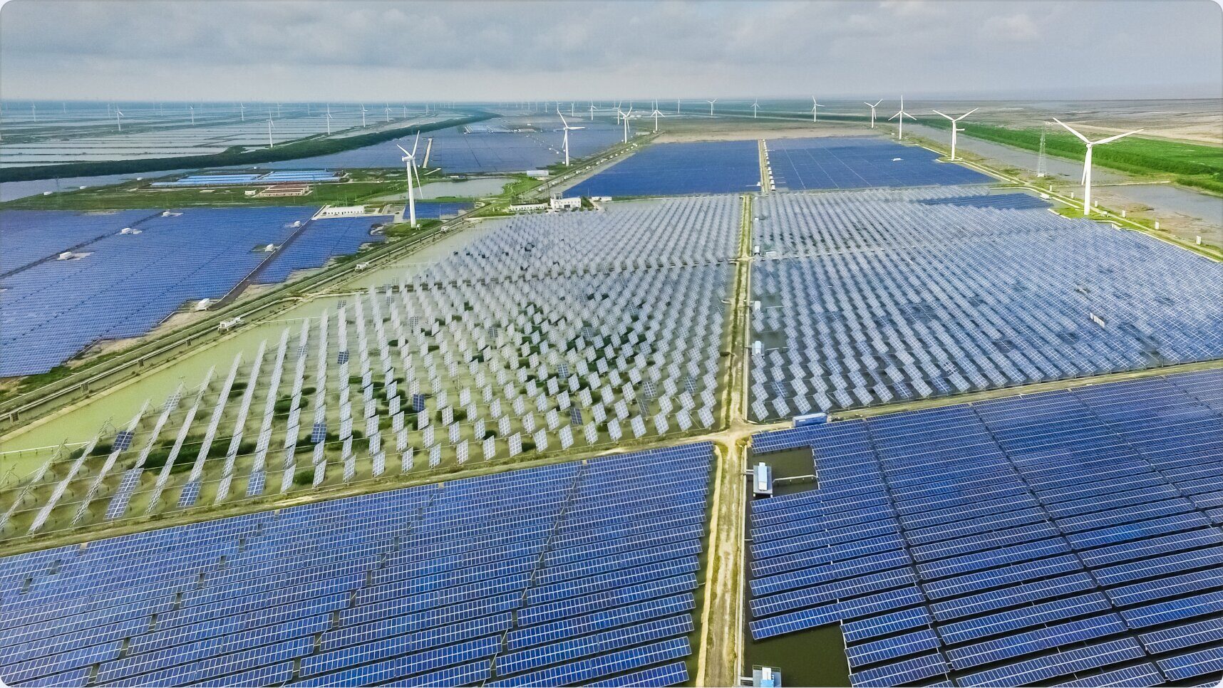 Панорама великої сонячної електростанції з вітрогенераторами на горизонті